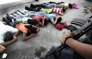 Civilians lie on the ground under police watch